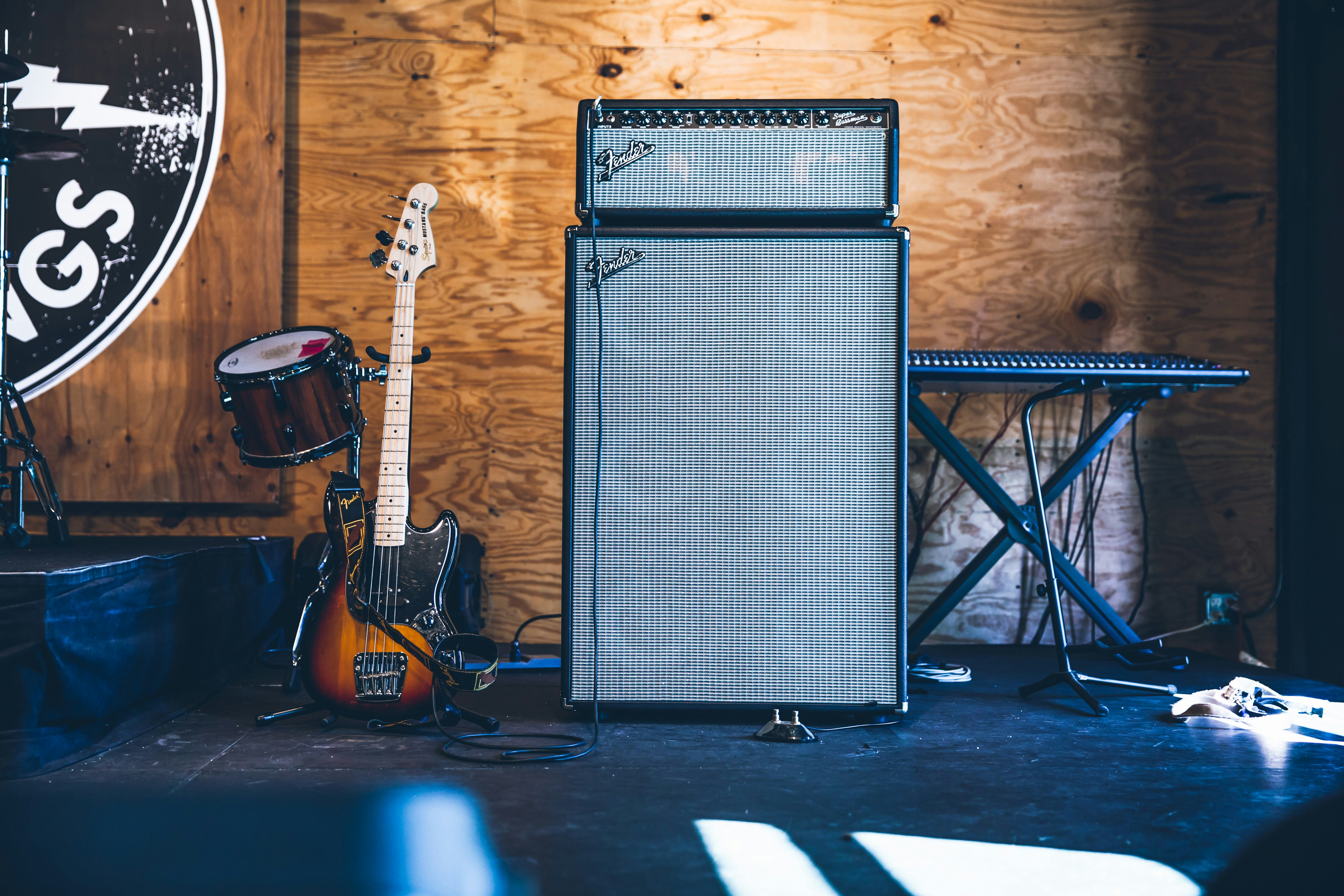 grey and black PA speakers near electric guitar and drum